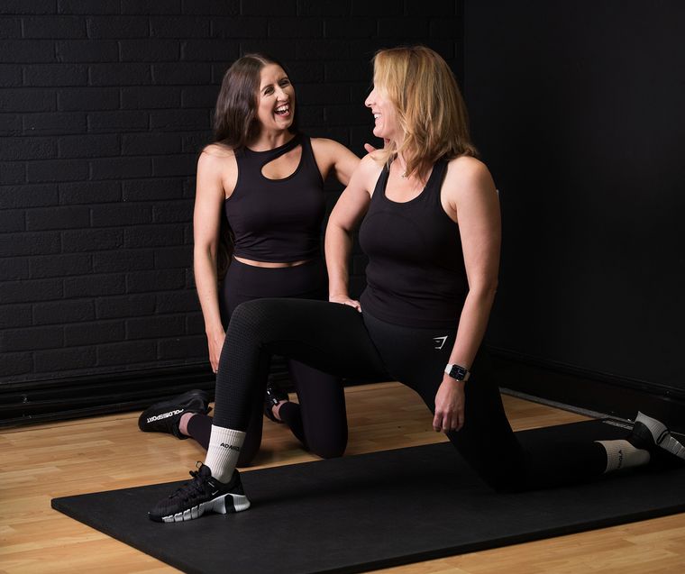 Elin Wyn kneeling on a mat beside a client during a stretch